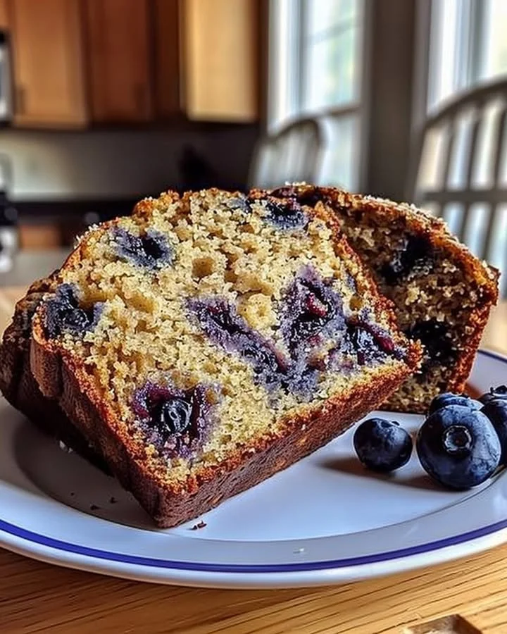 A slice of homemade Blueberry Banana Bread on a wooden cutting board.