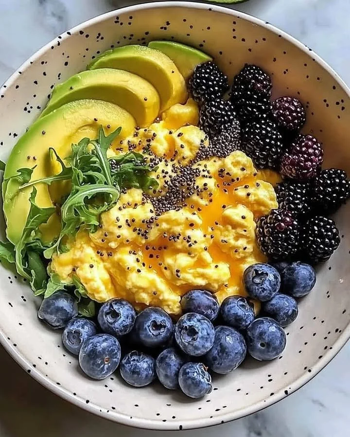 Healthy breakfast bowl with scrambled eggs, avocado slices, and mixed berries