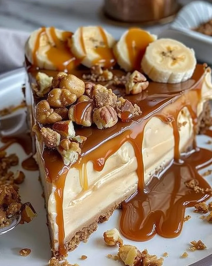 Delicious caramel banana crunch cheesecake topped with caramel drizzle and banana slices
