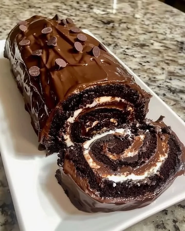 Delicious chocolate cake roll filled with creamy frosting and topped with chocolate glaze