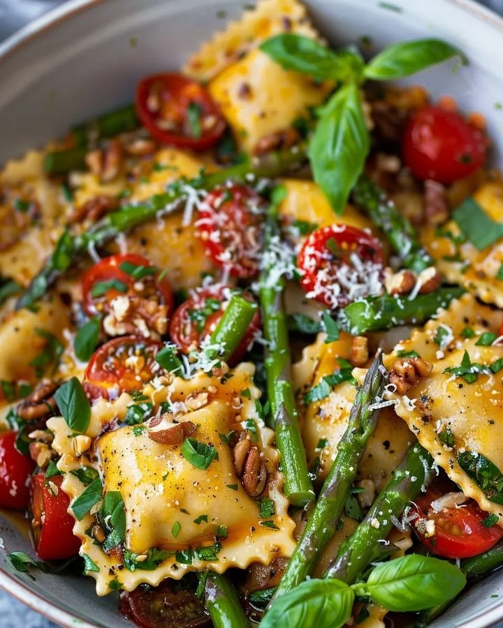 Delicious asparagus tomato ravioli toss garnished with fresh herbs