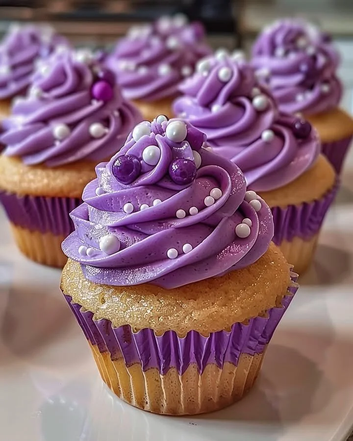 Grape soda cupcakes topped with purple frosting and grape candies.