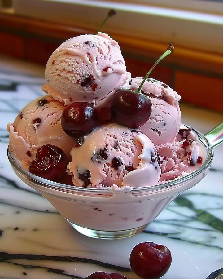 A bowl of homemade cherry ice cream with fresh cherries on top