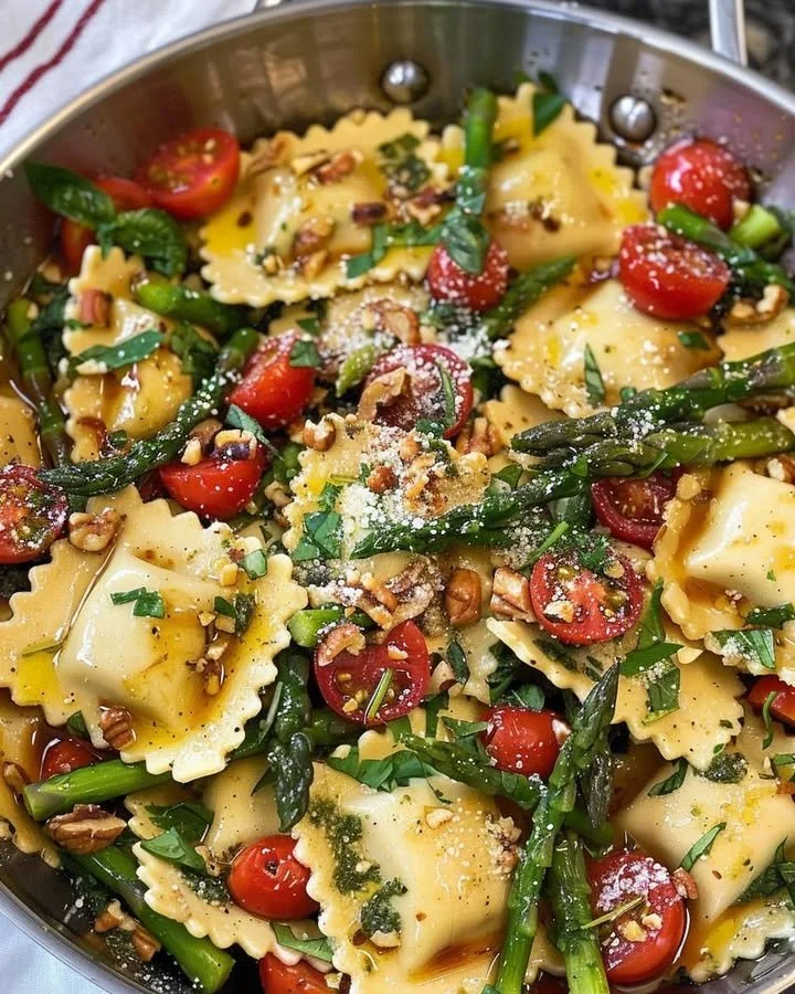 Ravioli with tomatoes, asparagus, garlic, and herbs plated beautifully.