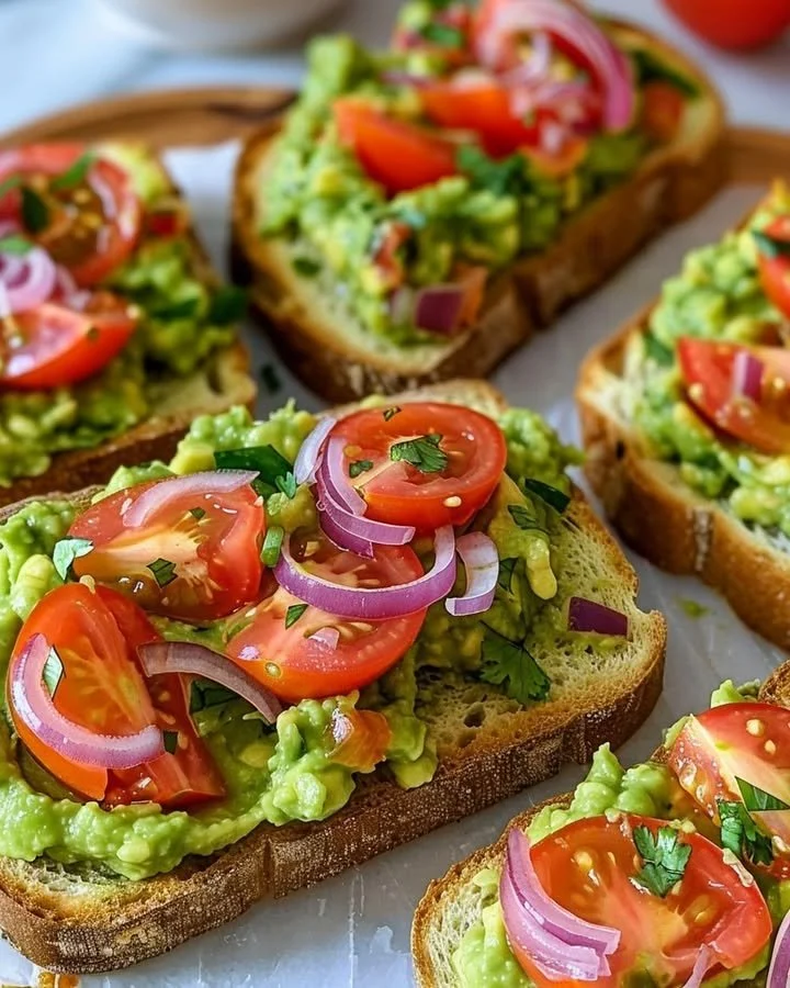 Image of smashed avocado bruschetta topped with tomatoes and herbs